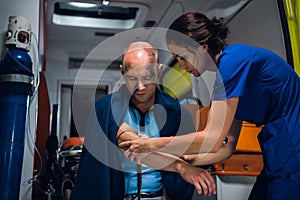 Woman in blue uniform wraps a tourniquet around a hand of injured man