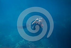 Woman in blue water, freediving photo. Freediver and coral reef landscape. Tropical island lagoon snorkeling