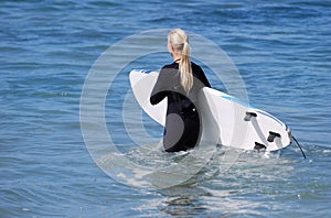 Woman board surfer heading out to the surf Laguna Beach, California.