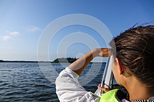 Woman in a boat looking out over the ocean and shades her eyes