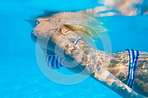 Woman body swims underwater in the swimming pool.