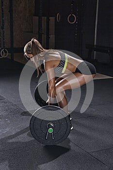 Woman bodybuilder prepare to do exercises with barbell in a gym.