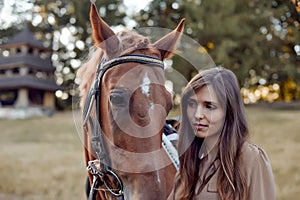 Woman bonds with her horse on a grassy field. Portrait of a young jockey highlights farm training and an outdoor saddle sports