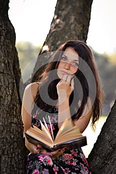 Brunette girl with black,fluffy hair read interesting book outdoors