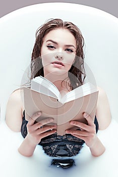 Woman with book lying in bath