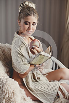 A woman with a book and a ripe apple in a hand