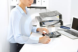 Woman bookkeeper or financial inspector calculating or checking balance, making report. Internal Revenue Service at work