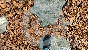 A woman in boots walks through the autumn park, forest in the Alps.First point view. Close-up of female legs in boots