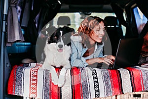 woman and border collie dog in a van. woman working on laptop. Travel concept