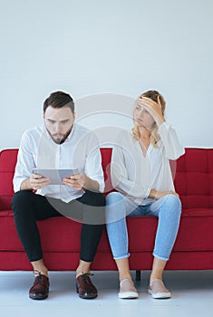 Woman bored and disregard to man sitting on couch in living room together,Family issues