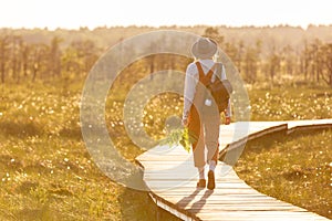 Woman botanist with backpack on ecological hiking trail in summer outdoors. Naturalist exploring wildlife and ecotourism adventure