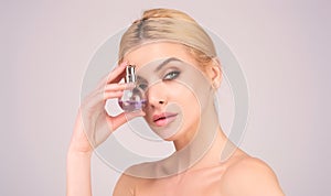 Woman with bottle of perfume smelling aroma.