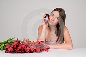 Woman with bottle of perfume smelling aroma.
