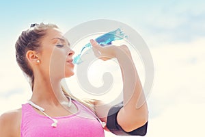 Woman with bottle of water after jogging on the beach