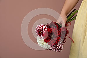 Woman with bouquet of beautiful dahlia flowers on brown background, closeup. Space for text
