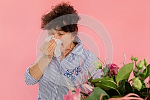 Woman bouquet of flowers hands take hankie sneezes closed eyes concept allergy illness discomfort pink background