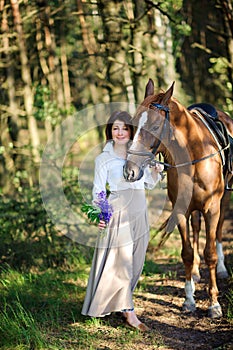 Woman with a bouquet of flowers walks with the favourite horse