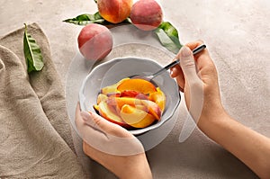 Woman with bowl full of sliced peaches at light table