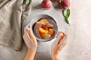 Woman with bowl full of sliced peaches at light table