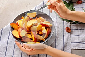 Woman with bowl full of sliced peaches at light table