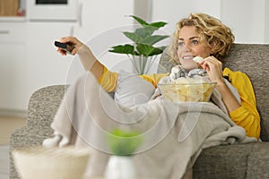 woman with bowl potato chips watching tv on sofa