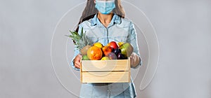 Woman with box full of fresh fruit protecting with face mask
