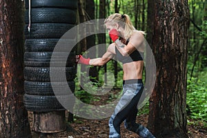 Woman boxer doing uppercut kick working out outdoors. photo
