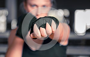 Woman boxer getting ready to fight. Horizontal shot of stylish young woman boxer wearing handwraps training indoors