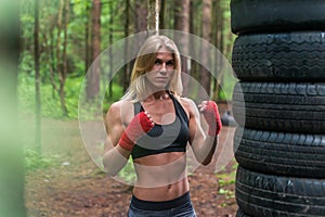 Woman boxer professional fighter posing in boxing stance, working out outdoors