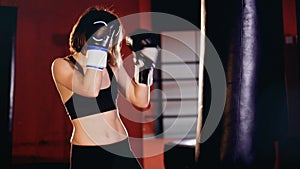 Woman boxer training in gym, boxing punching bag.