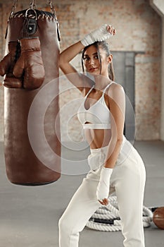 Woman boxer training with a punching bag in gym. Boxing girl wearing hand wrap