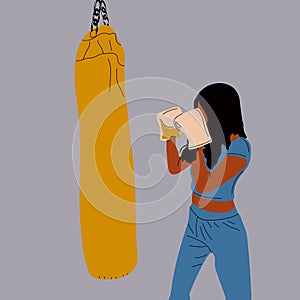 Woman in boxing gloves posing at punching bag in sportswear.