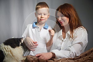 Woman with a boy and cat. Mom with son and pet on a white background. Family portrait with mother and boy having fun