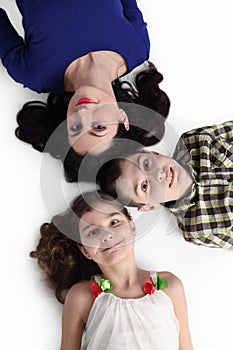 Woman, boy and girl lie on floor on gray