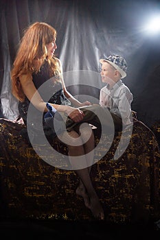 Woman with a boy in hat. Mom with son on a dark background. Family portrait with mother with red hair and boy having fun