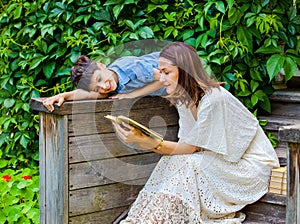 Woman and a boy are reading a book on an ancient wooden porch