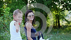 A woman and a boy are walking around the field, son is riding a pony, mother is holding a pony for a bridle. Cheerful