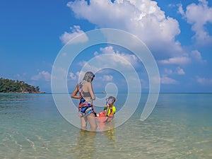 Woman and boy wearing a life jacket, scuba diving in the sea.