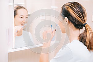 Woman with braces cleans her teeth with a toothbrush, before mirror. Selective focus on the person.