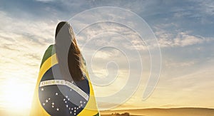 Woman with Brazilian flag looking the sunset