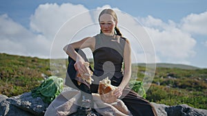 Woman breaking homemade bread in sunlight. Traveler enjoying picnic in mountains