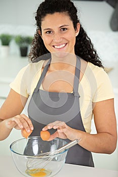 woman breaks white egg into bowl