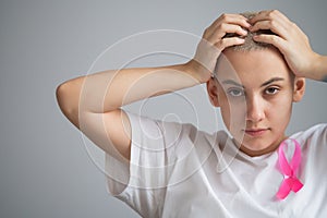 Woman with breast cancer holding her head on white background.