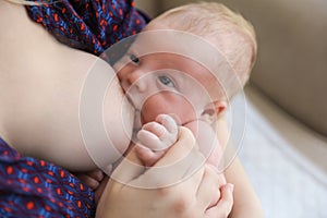 Woman breast feeding her little baby at home, closeup