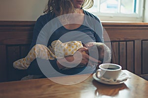Woman breastfeeding baby in cafe