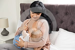 Woman breastfeeding her little baby on bed