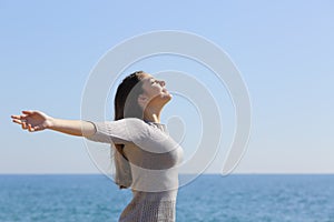 Woman breathing deep fresh air and raising arms