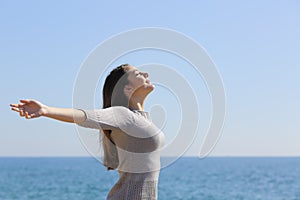 Woman breathing deep fresh air and raising arms photo