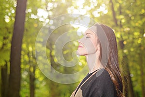 Woman breathing fresh air in a green forest in spring wearing a wool poncho