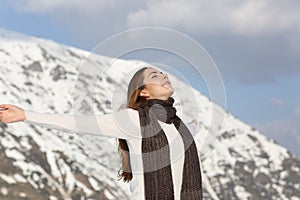 Woman breathing fresh air raising arms in winter